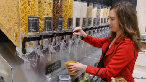 A shopper in Waitrose filling a reusable container with pasta