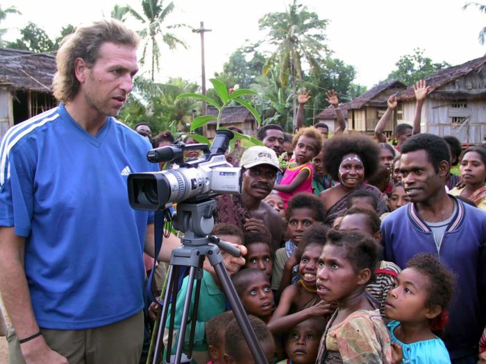 Julian Newman with a filming camera and a group of people in an Indonesian village